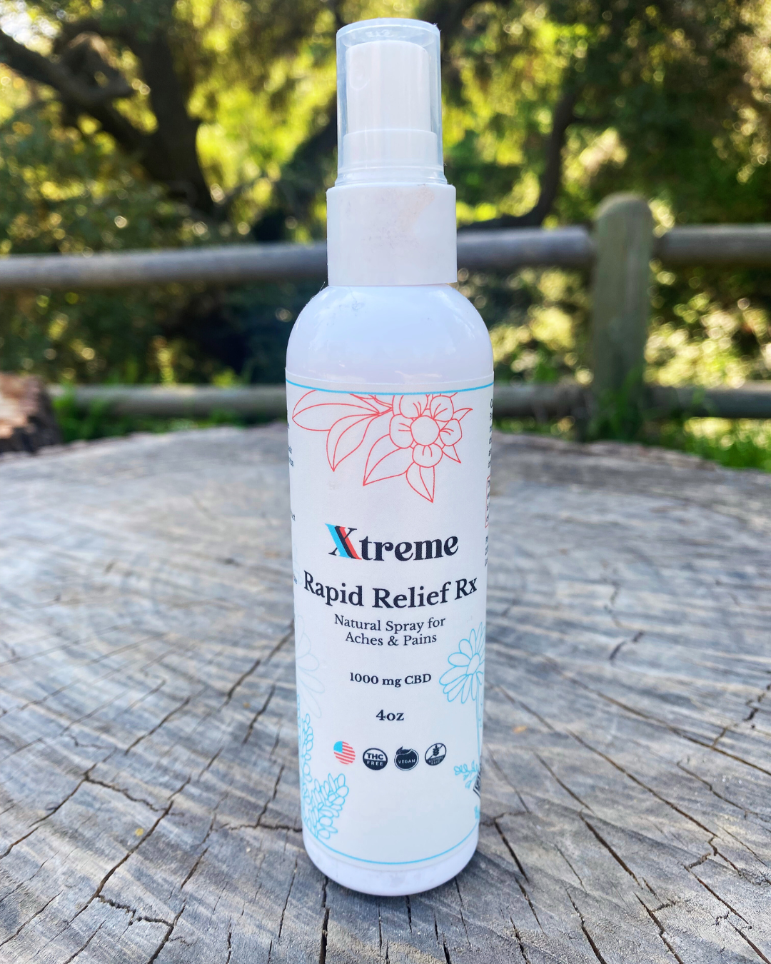 Xtreme Brands RX Rapid Relief Spray on a tree stump outdoors – strongest doctor-trusted formula with full-spectrum hemp, Arnica, and Menthol for fast, hands-free pain relief.