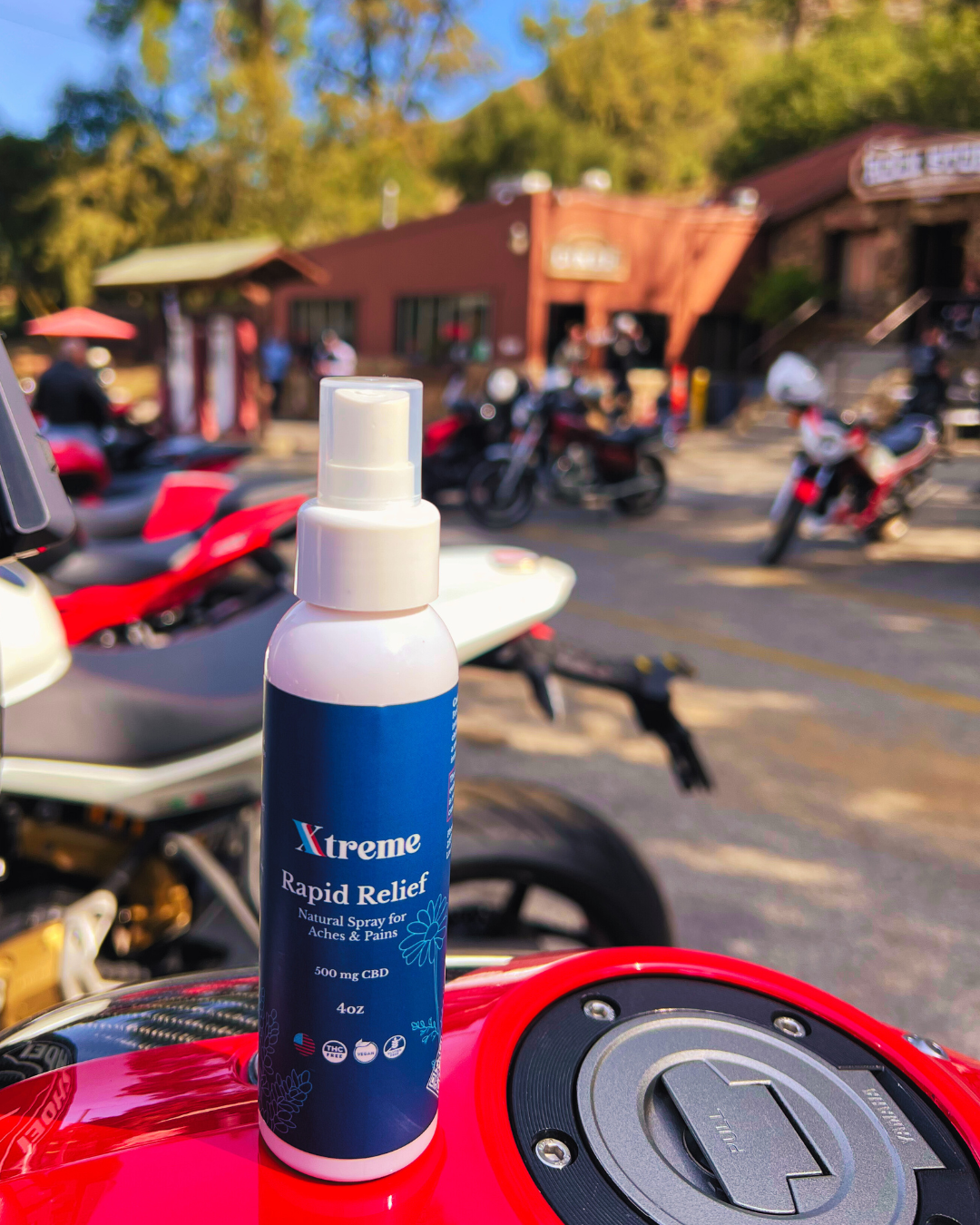 Xtreme Rapid Relief Natural Spray in front of motorcycles – USA-made, doctor-trusted hemp-derived CBD formula with Arnica, Turmeric, and Willow Bark for everyday muscle and joint relief.