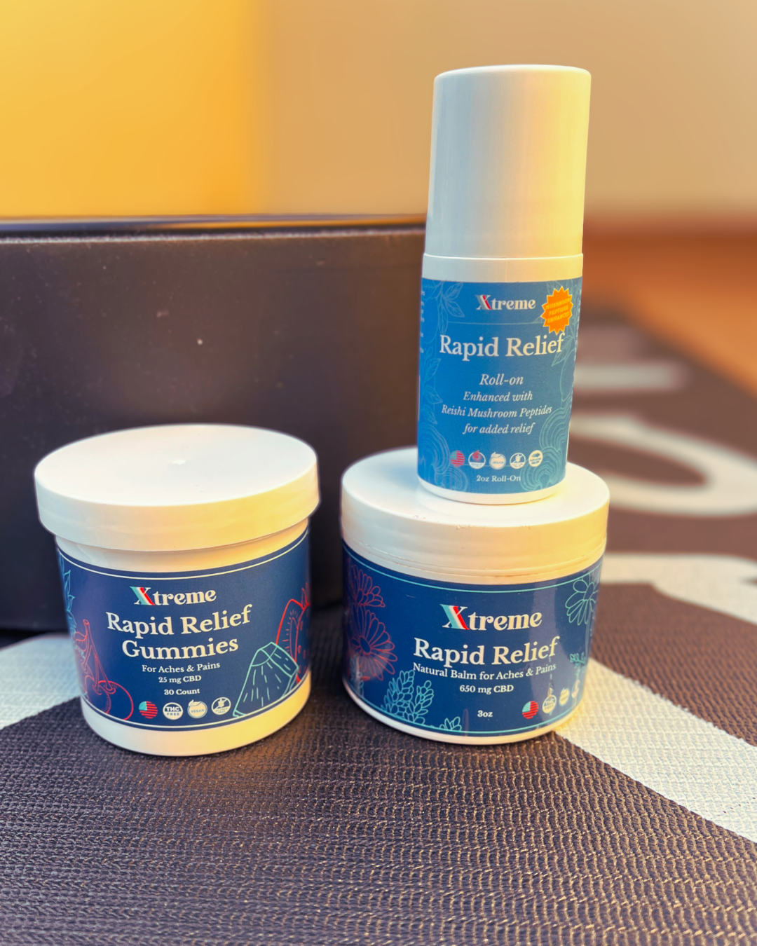 Xtreme Brands Recovery Bundle – RX Rapid Relief Balm, RX Rapid Relief Spray, and Functional Mushroom Roll-On on a yoga mat in a gym setting for natural pain relief and recovery.
