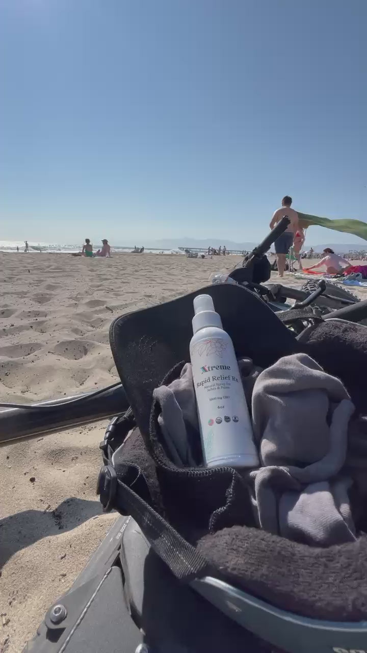 Xtreme Brands RX Rapid Relief Spray on a moped at the beach – strongest doctor-trusted formula with full-spectrum hemp, Arnica, and Menthol for fast, hands-free pain relief.