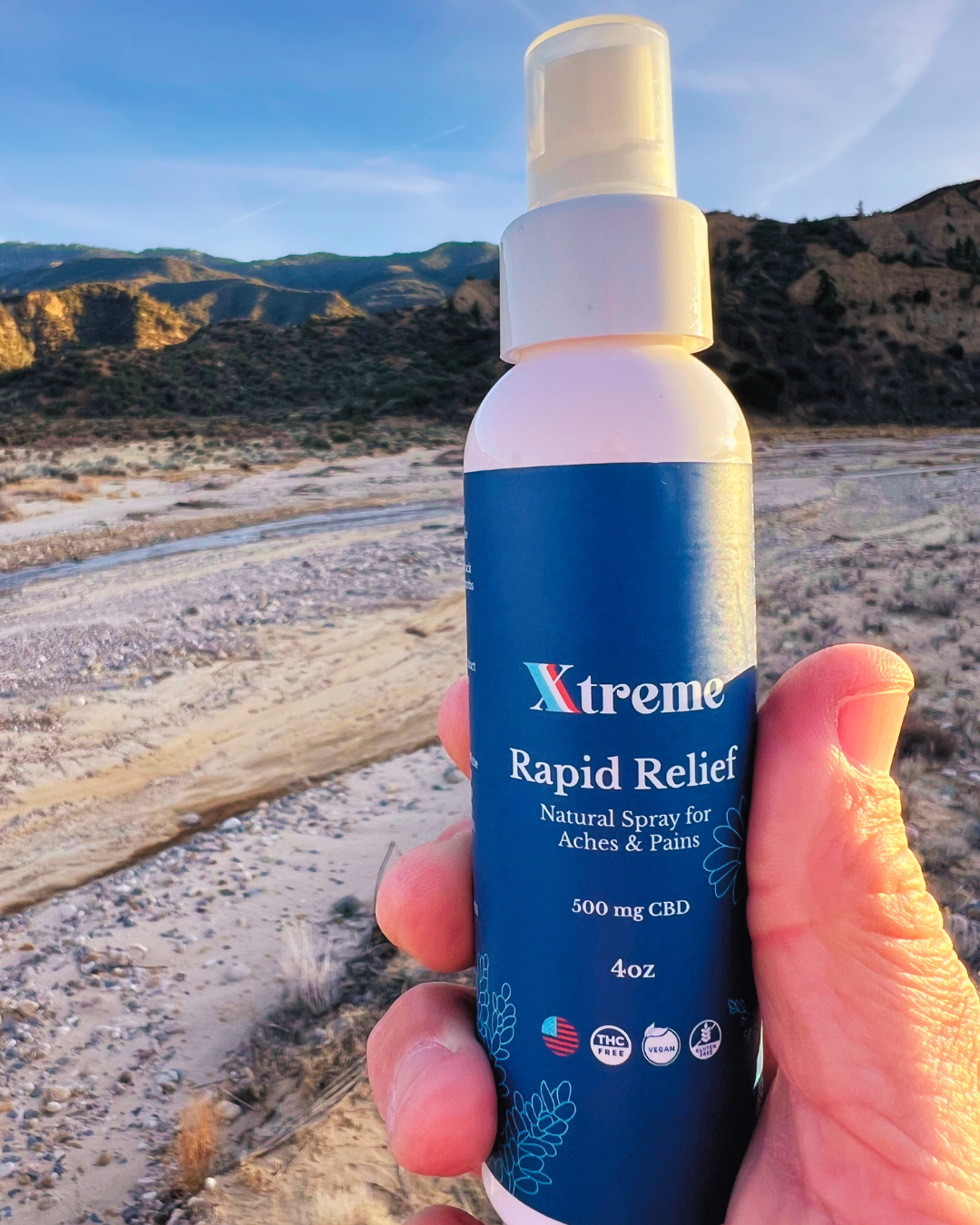 Xtreme Rapid Relief Natural Spray bottle outdoors in nature- botanical ingredients delivering on-the-spot pain relief for active lifestyles.